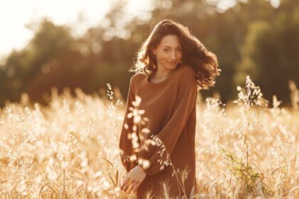 A stylish woman wearing her favorite sweater while moving through a summer field.